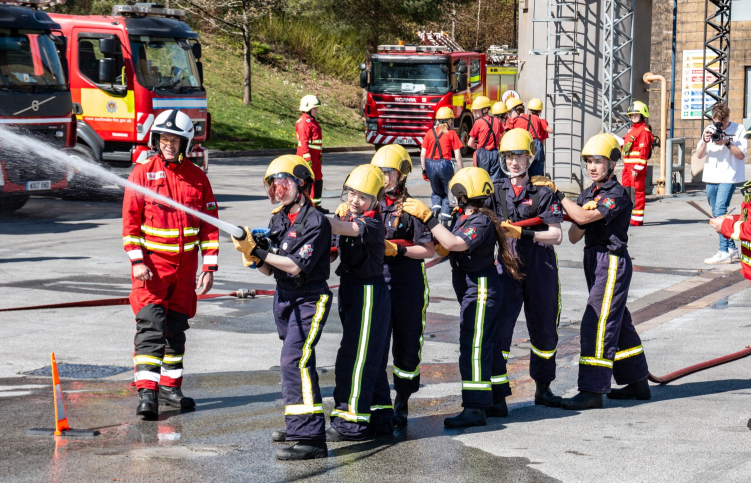 Fire Cadets performing a drill exercise with hose in a fire and rescue service yard